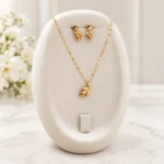 مدال و جفت گوشواره طلا طرح خوشه روی استند کرم؛ عکس دکوراتیو